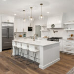 beautiful kitchen in new luxury home with island, pendant lights, and hardwood floors